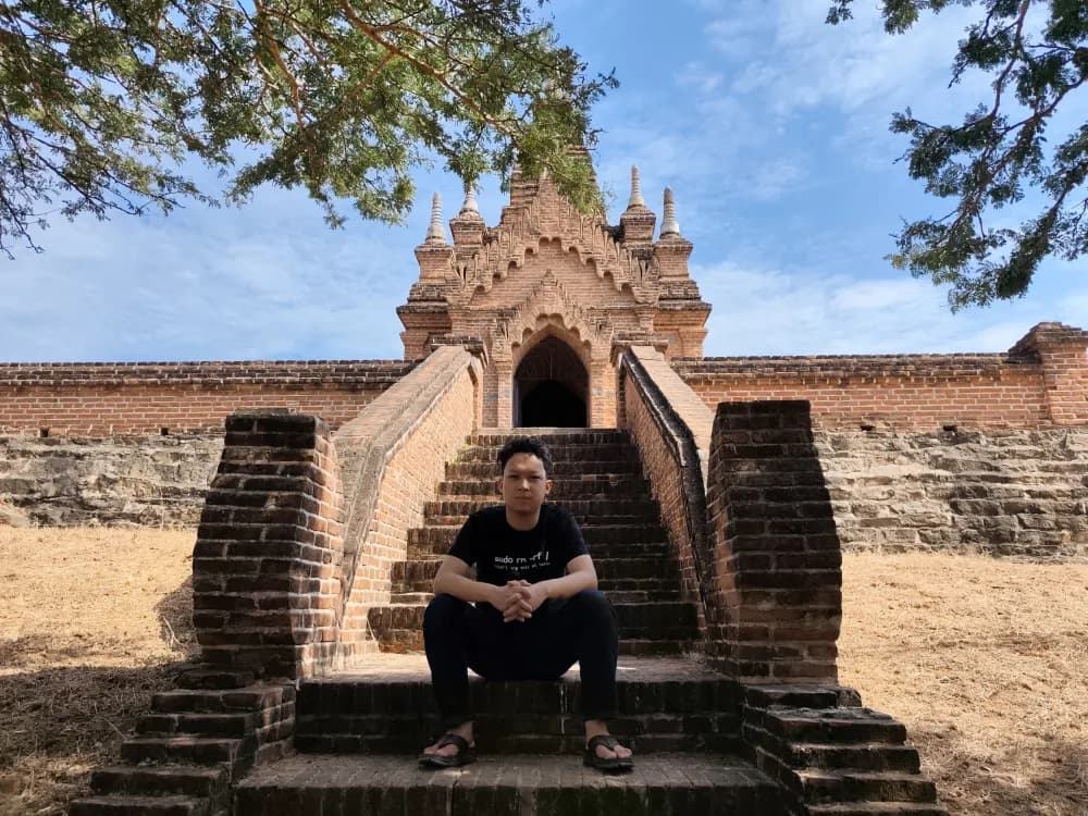 Htet Zaw Phyo seated on the steps of a historic brick temple in Bagan